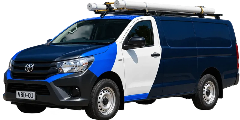 A licensed Abbotsford plumbing van loaded with pipe on the roof rack